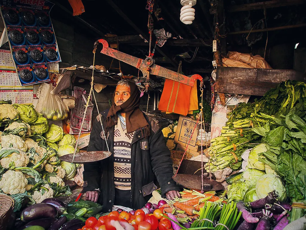 A vegetable trader weighing produce at a market stall in Darjeeling