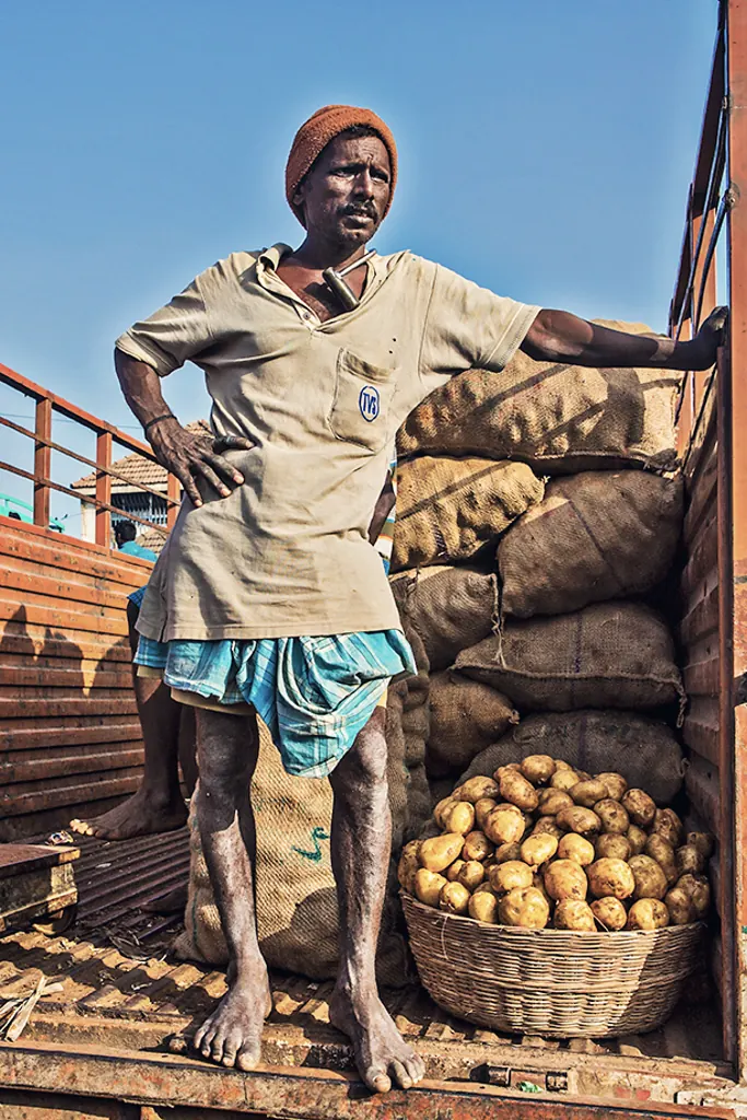 A porter standing beside sacks of potatoes at Koyambedu market in Chennai