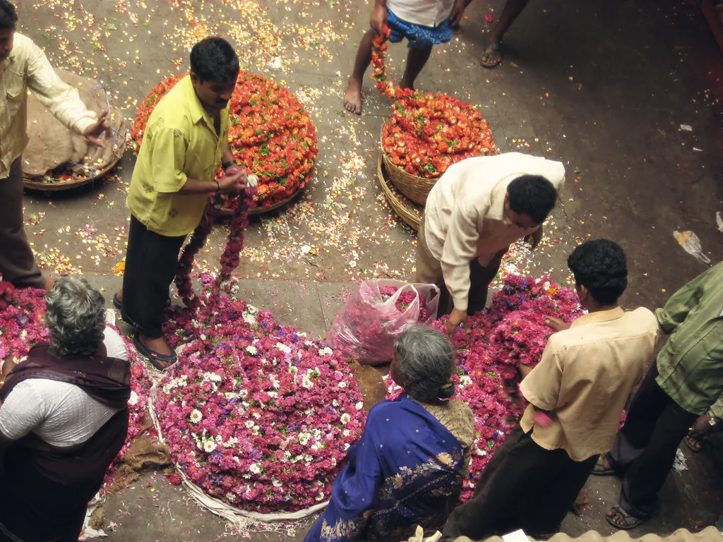 Flower traders sorting heaps of marigolds and roses at a city market